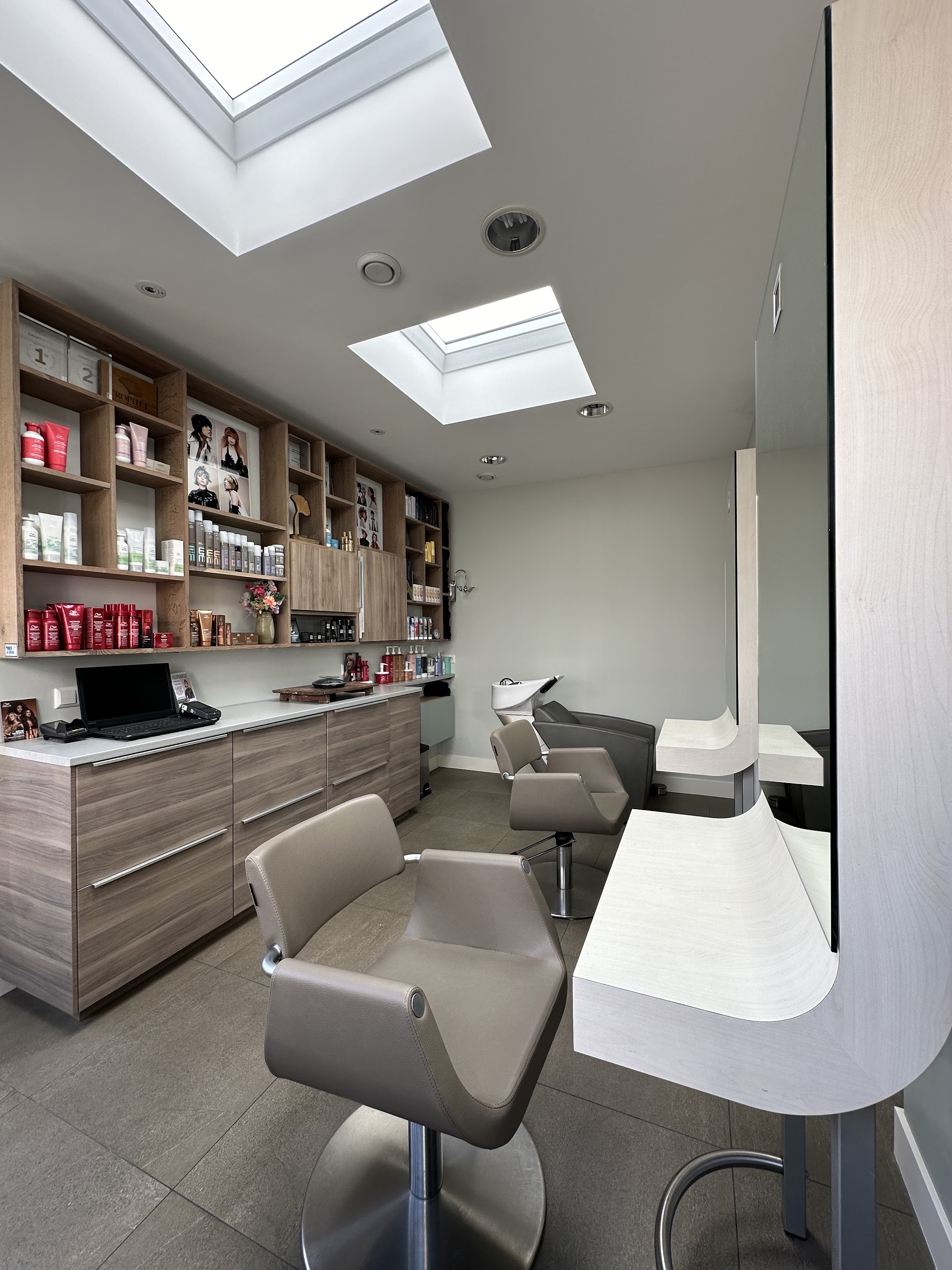 De salon met lichtkoepels, wasunit, kappersstoelen en wandkasten met haarproducten