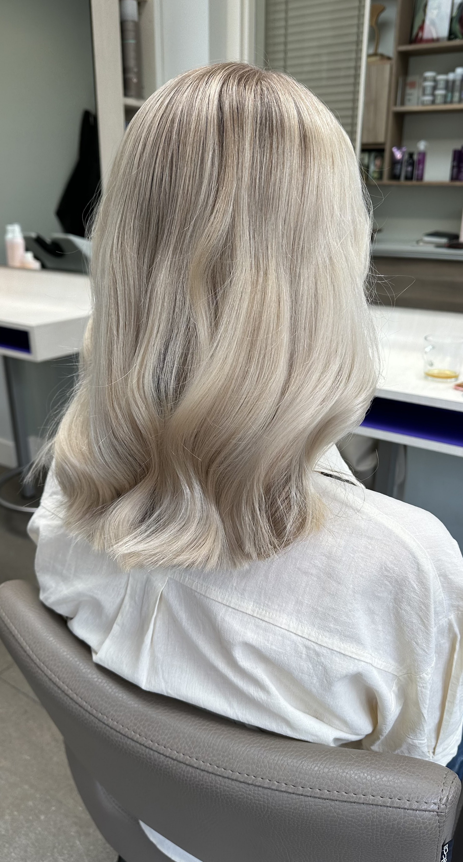Platinablond haar tot op de schouders, van achteren gezien in de salonstoel