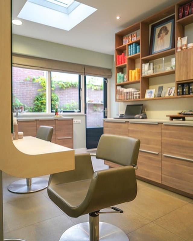 De salon met raam, wandkasten vol producten en ingelijste foto’s aan de wand